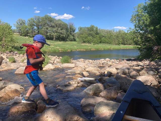 Family microadventure idea - boy hopping rocks on a creek