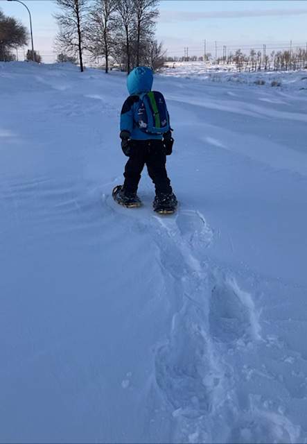 boy snowshoeing. Snowshoe prints behind him